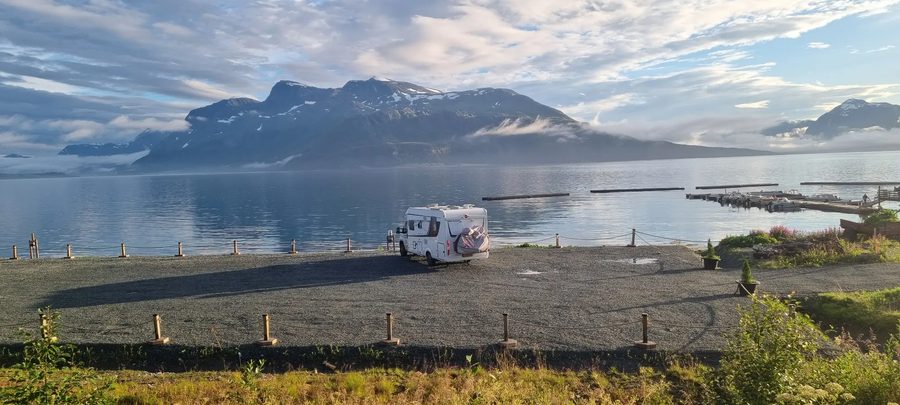 De camper op een grindparkeerplaats aan het water bij zonsopkomst