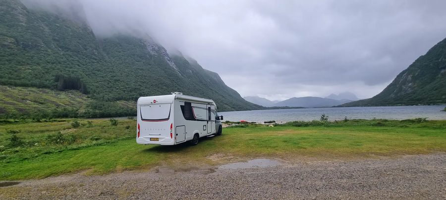 De camper aan een Noorse fjord met laaghangende mist boven de bergen