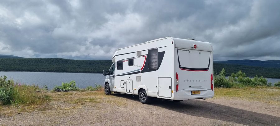 De camper aan het water onder een donkere, wolkachtige hemel in Scandinavië